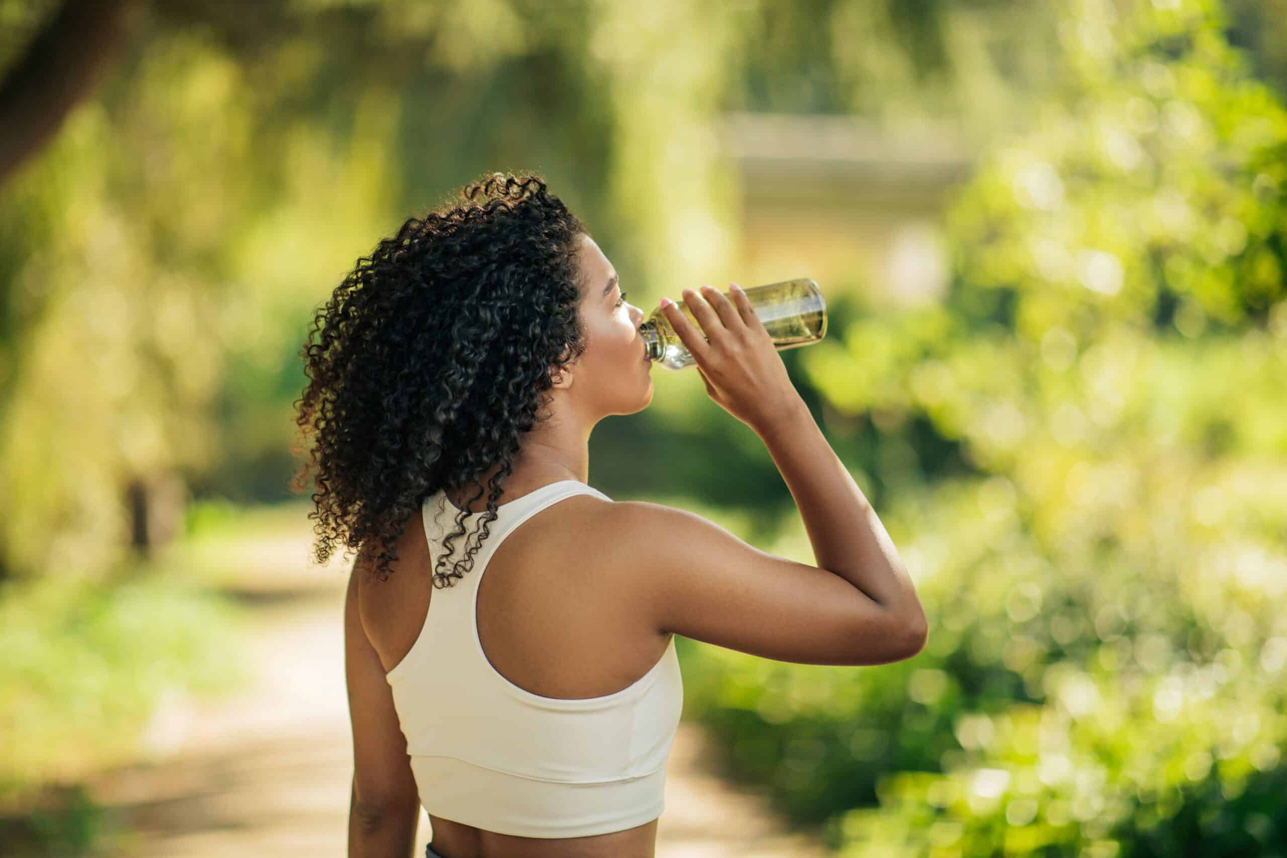 Eine sportliche Frau trinkt Wasser