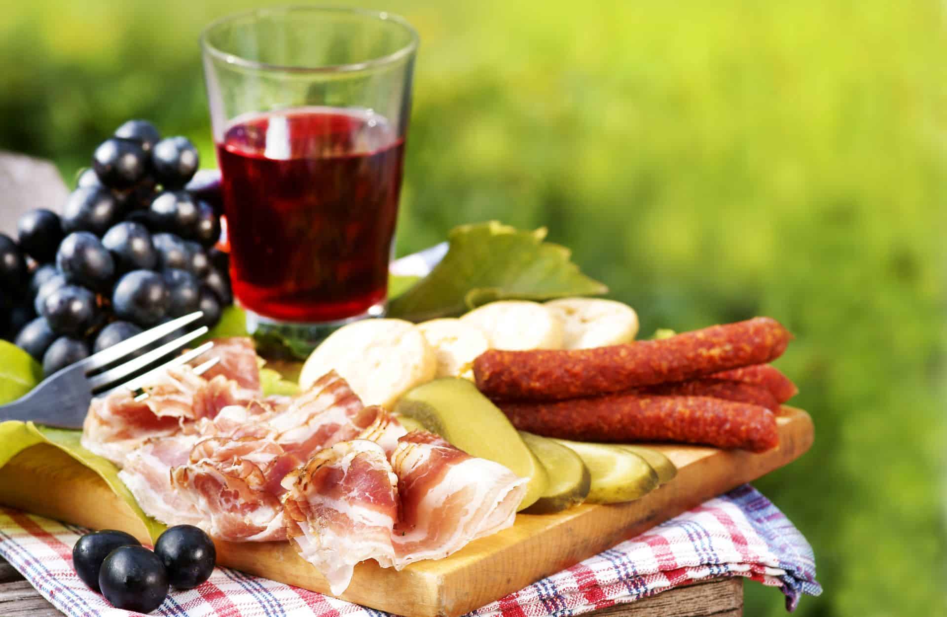 Jausenplatte mit Kaminwurzen, Speck, Gurken und Rotwein.